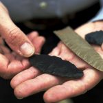 Clovis-made stone tools in the hands of Bruce Bradley, co-author of Across Atlantic Ice: The Origin of America’s Clovis Culture. (Photo by Jim Wileman)